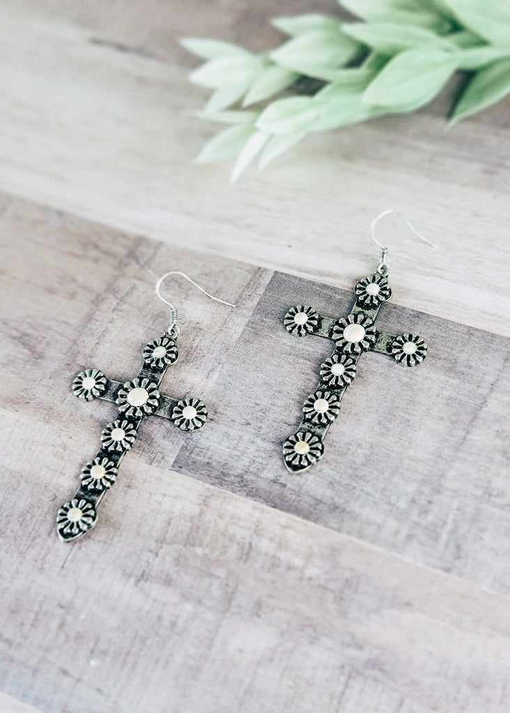 White Western Concho Cross Earrings on wood background with green decor