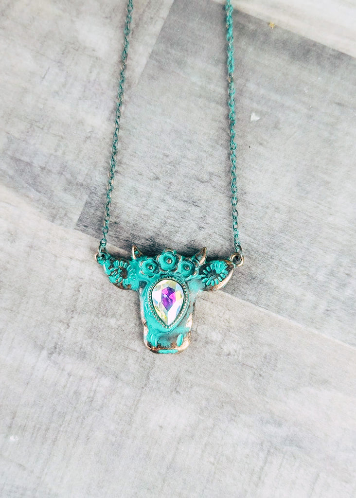 patina rhinestone cow necklace on wood background