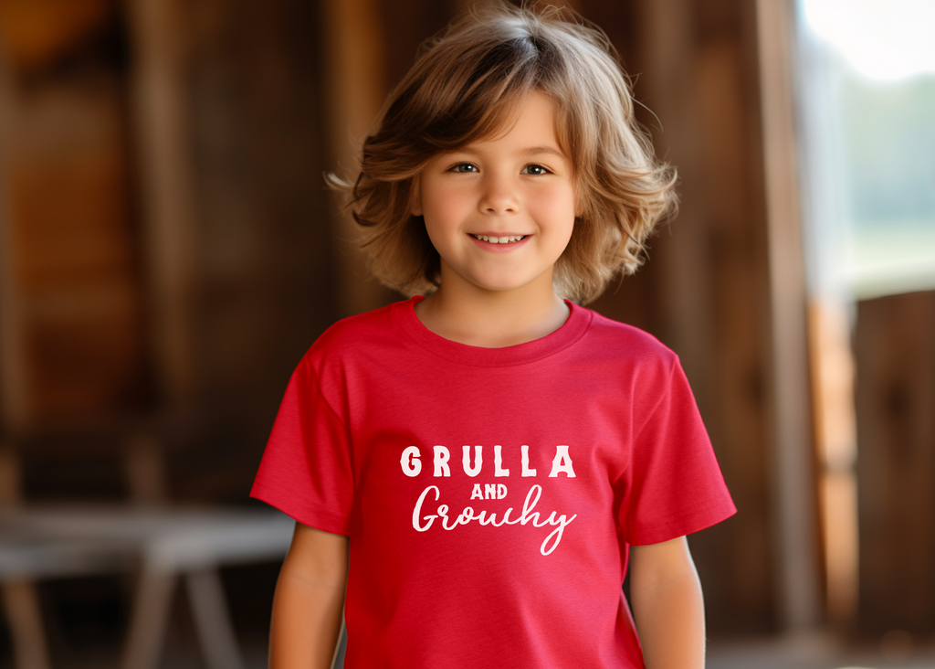 Red short sleeve with white lettering reading "Grulla and Grouchy". Model wears this in a barn. 