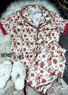 red and cream santa bronc silky pajamas laying on a white fluffy rug with white slippers and disco ball decor 