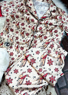 red and cream santa bronc silky pajamas laying on a white fluffy rug with white slippers and disco ball decor 