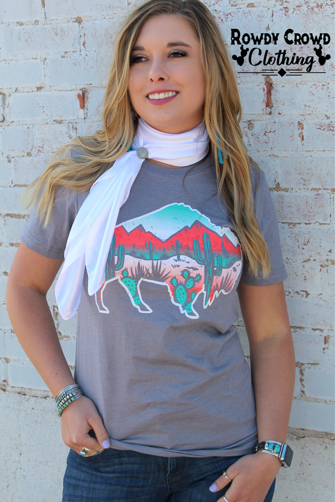 Grey short sleeve with a white outlined background and a desert scene inside of the buffalo. Red and shades of turquoise make up the desert scene (mountains and cacti). 
