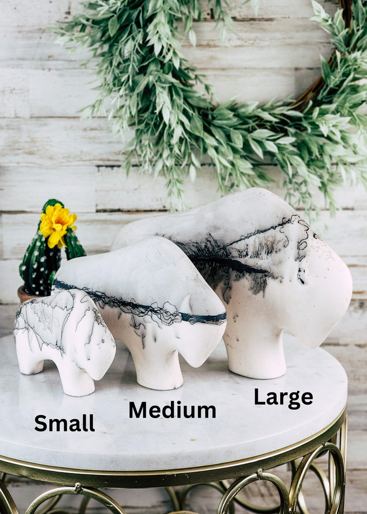 Horse hair buffalo with think hair line down the center of the buffalo. Grey top and white bottom are separated by horse hair. The buffalo is displayed on marble table top. Different sizes are shown. 