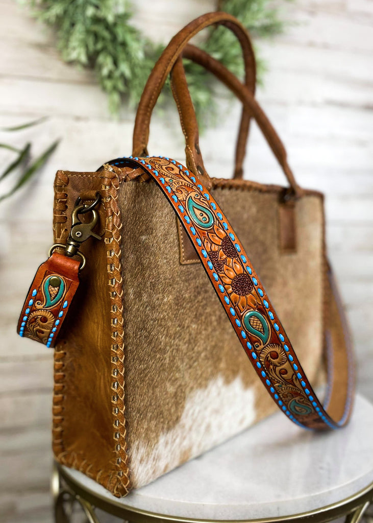 Amber & Blue Floral Paisley Purse Strap taken on brown cowhide handbag on white table with green floral décor 