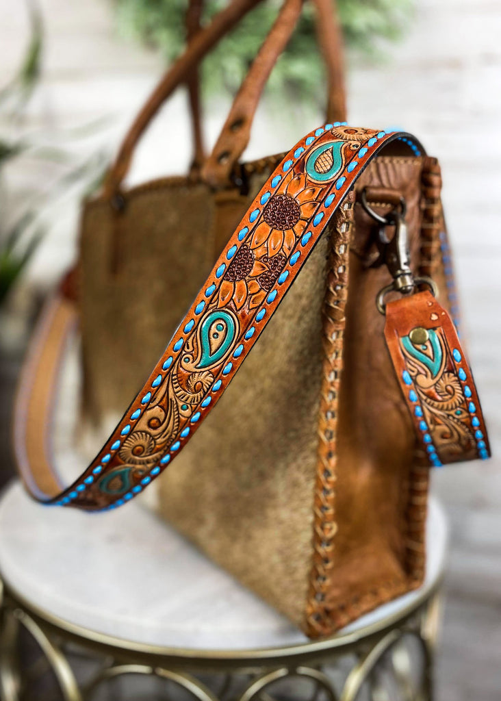 Amber & Blue Floral Paisley Purse Strap taken on brown cowhide handbag on white table with green floral décor 