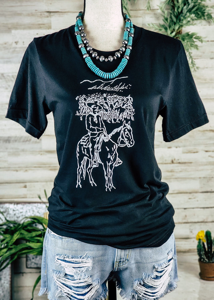Black short sleeve tee with white printed Ranchero graphic. Short hangs on mannequin with turquoise choker and jean shorts. 