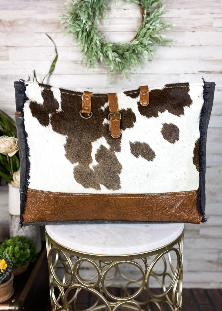 Cowhide with bottom floral tooled paneling. Matching straps and buckle. Frayed edges on the side with a side open pocket.  Style A