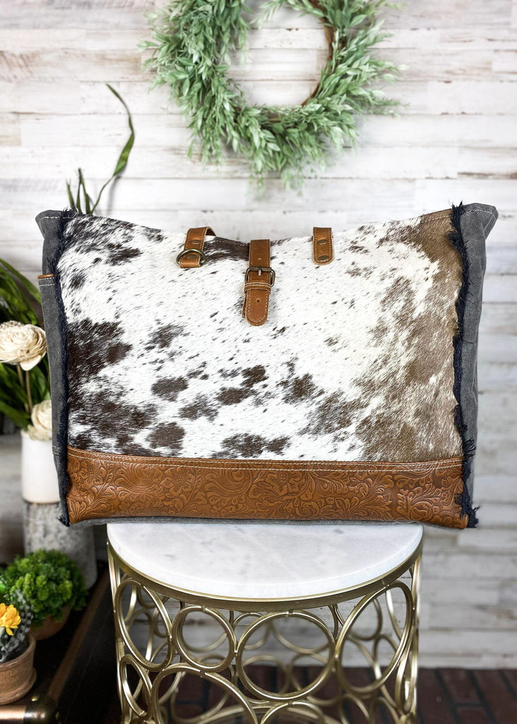 Cowhide with bottom floral tooled paneling. Matching straps and buckle. Frayed edges on the side with a side open pocket.  Style B