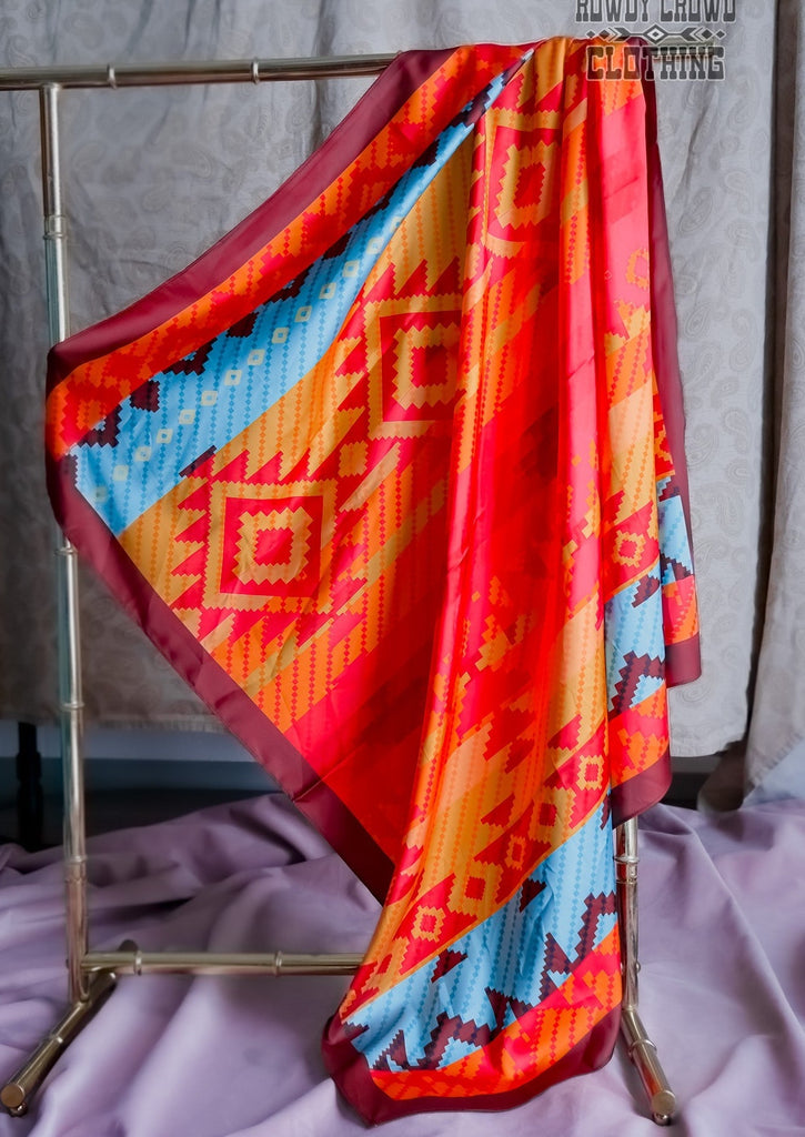 Western wild rag with bright reds and orange tribal design and two strips of turquoise and maroon. 