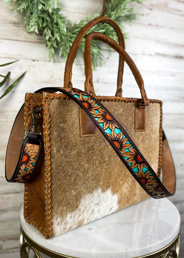 Dusk Sunflower Purse Strap taken on brown cowhide handbag on white table with green floral décor 