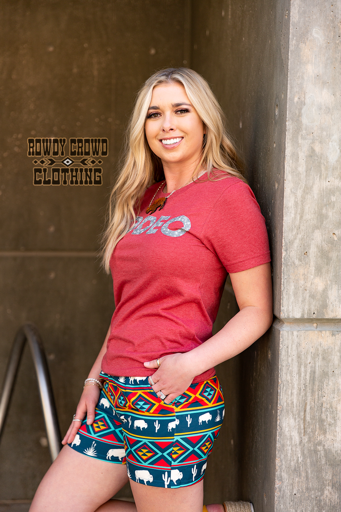 Southwestern buffalo shorts coming to about mid thigh. Model wears these leaning against a wall with a red shirt.