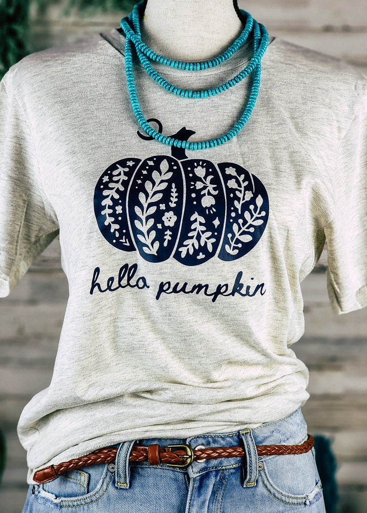 Heather natural short sleeve with black floral pumpkin with black lettering reading "hello pumpkin".  Tee hangs from mannequin with jean shorts and western necklace. 