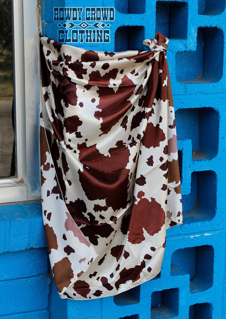 Brown cowhide print wild rag. Wild rag hangs from blue brick. 