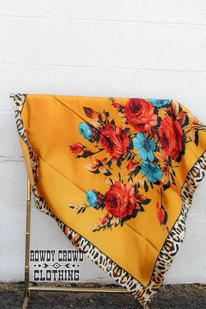 Fiesty floral wild rag with leopard print boarders and yellow main colors. Pops of color are added with the floral print. Wild rag hang from a metal rack. 