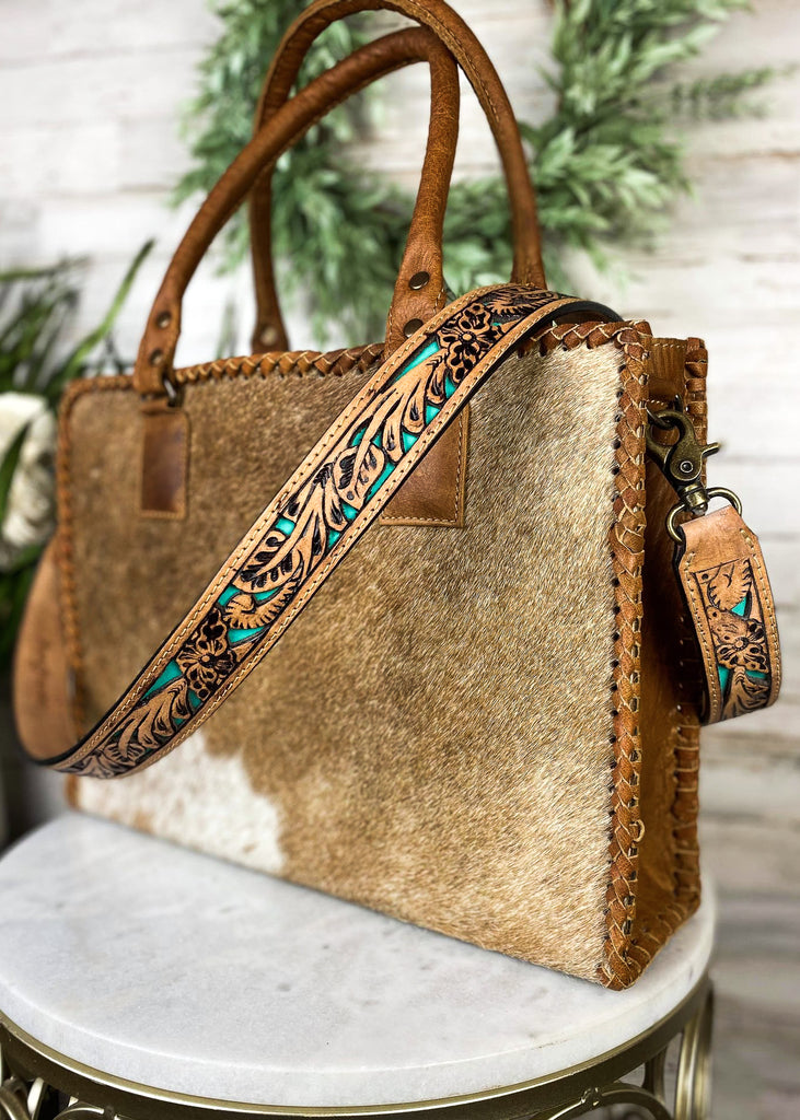 Brown purse strap with floral tooled detail and teal color detail, taken on handbag 