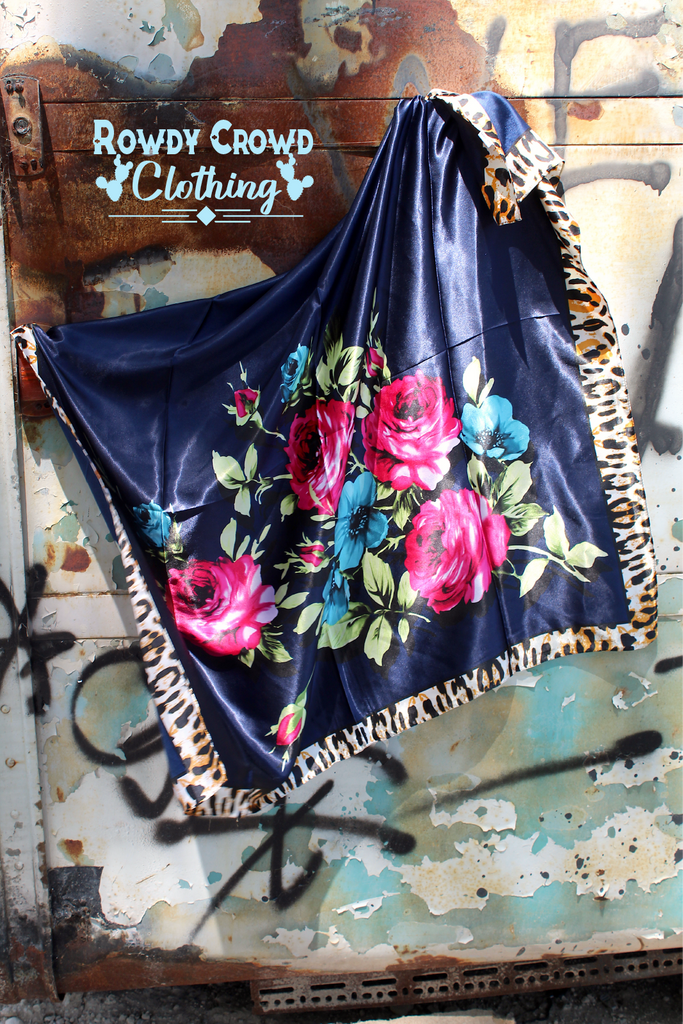 Fiesty floral wild rag with leopard print boarders and navy main colors. Pops of color are added with the floral print. Wild rag hang from a grafiti wall. 