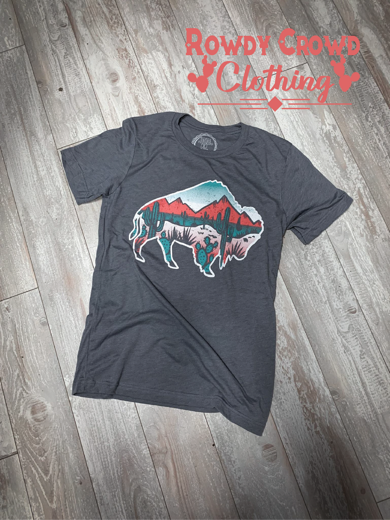 Grey short sleeve with a white outlined background and a desert scene inside of the buffalo. Red and shades of turquoise make up the desert scene (mountains and cacti). 