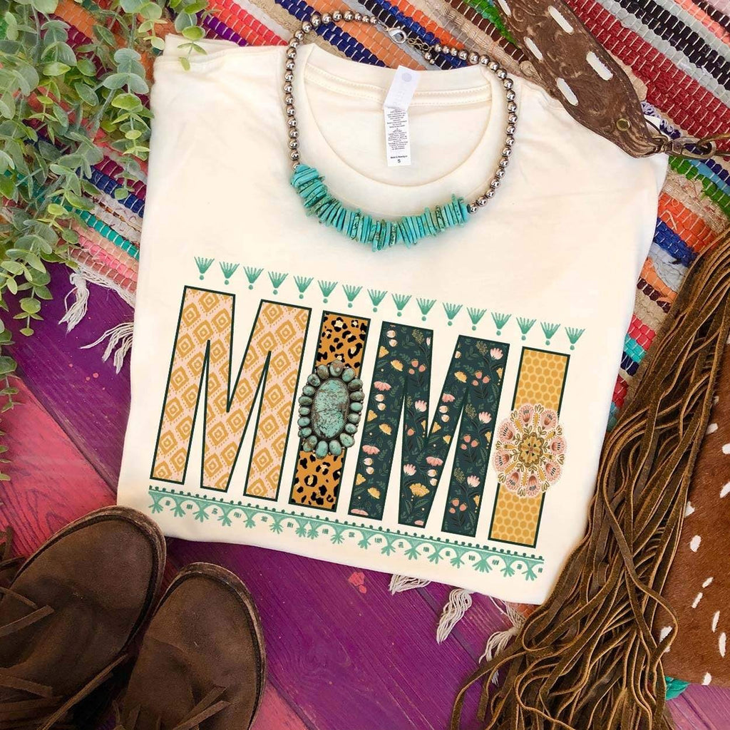 Cream short sleeve tee with large letters reading "MIMI". Multi patterns are on the lettering. Blue bordering are on the top and bottom of the word.