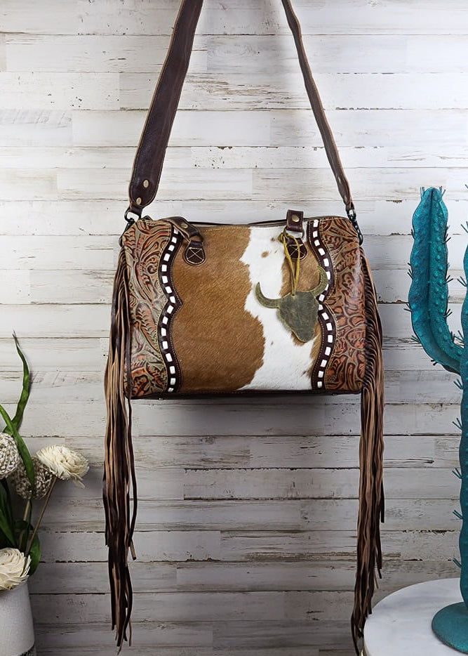 Cowhide & Steer Skull Crossbody Handbag [Style A] hanging on wood wall with green decor