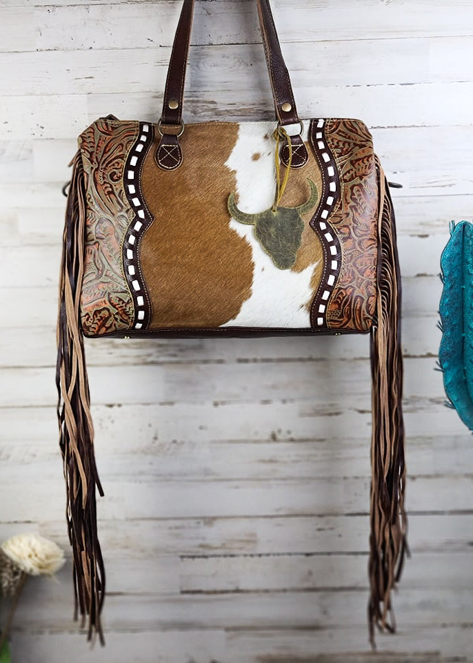 Cowhide & Steer Skull Crossbody Handbag [Style A] hanging on wood wall with green decor