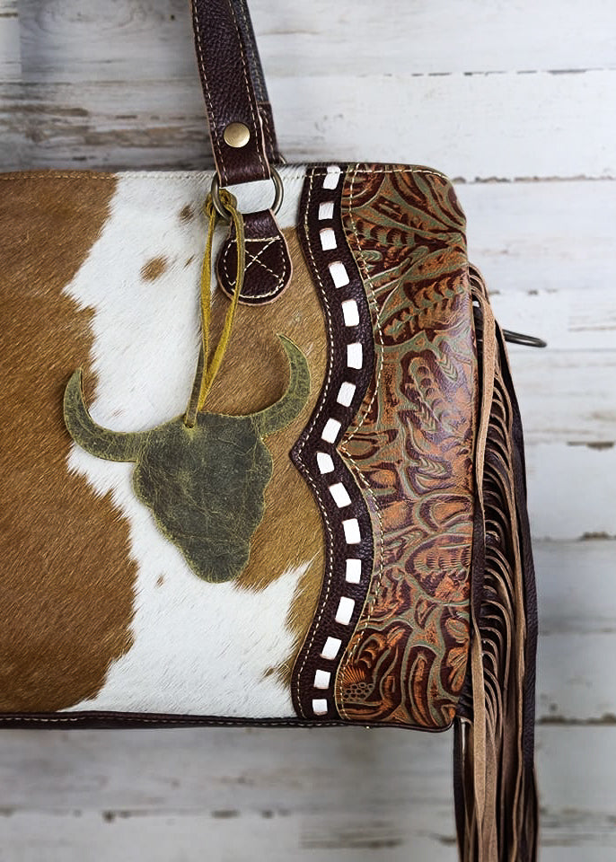 Cowhide & Steer Skull Crossbody Handbag [Style A] hanging on wood wall with green decor