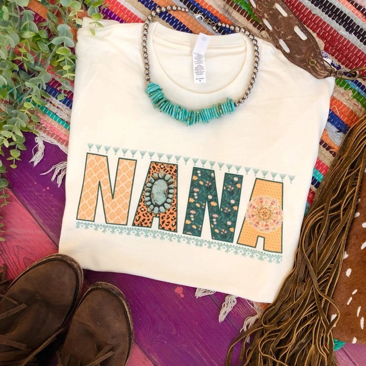 Cream short sleeve tee with large letters reading "NANA". Multi patterns are on the lettering. Blue bordering are on the top and bottom of the word.
