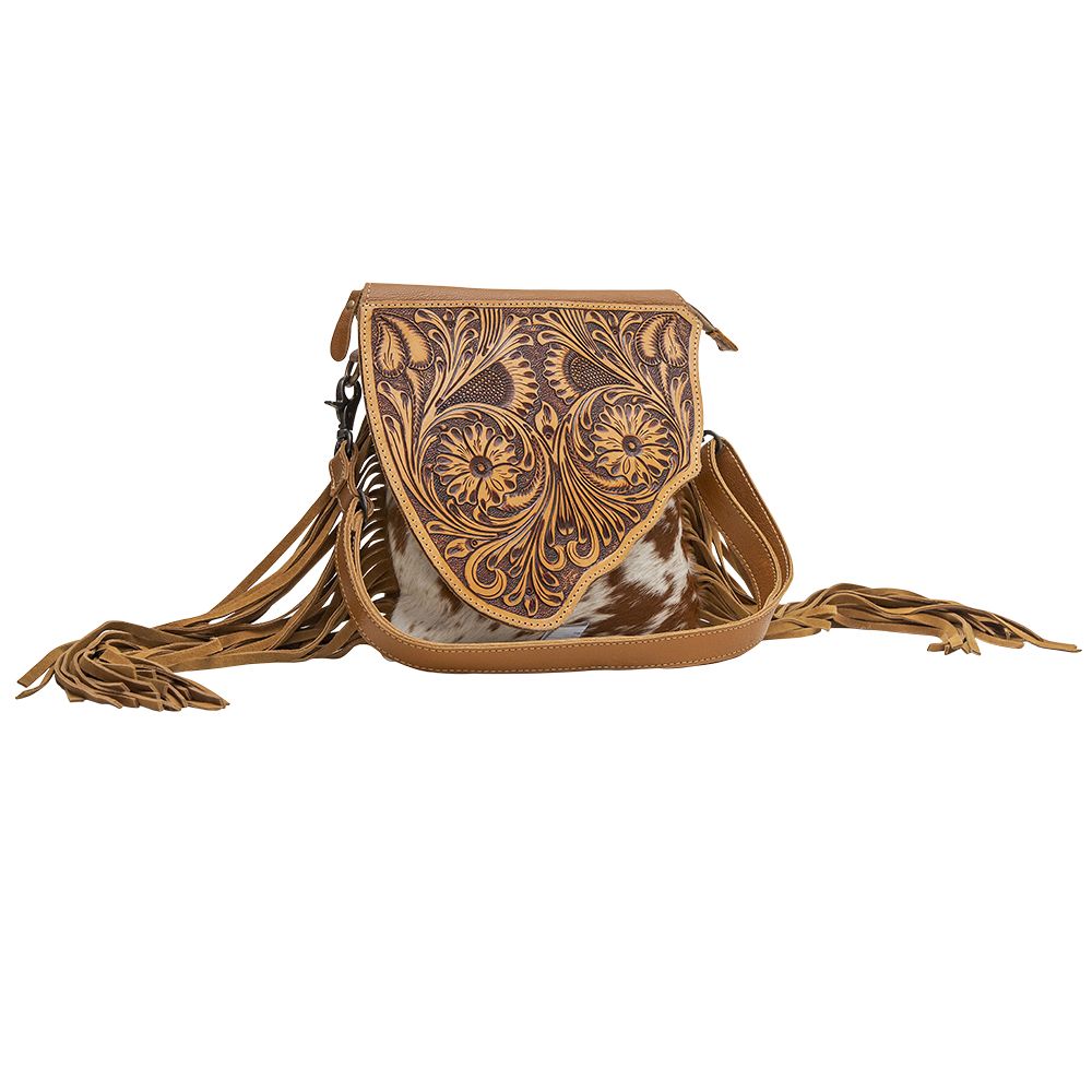 Concealed carry cowhide purse with floral tooled leather panel on the top. Fringe hangs from the side of the purse with adjustable shoulder strap. Purse is shown on a white background. 