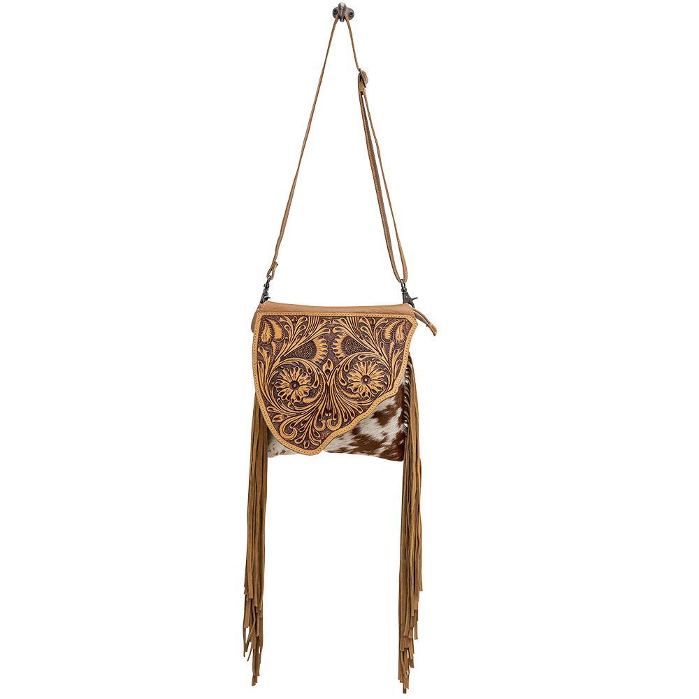 Concealed carry cowhide purse with floral tooled leather panel on the top. Fringe hangs from the side of the purse with adjustable shoulder strap. 