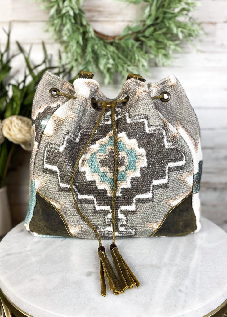 Temple Aztec Bucket Handbag on white table with green decor, front view with drawstrings