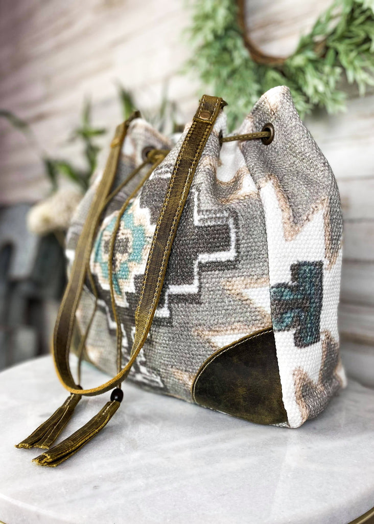 Temple Aztec Bucket Handbag on white table with green decor, front view with drawstrings